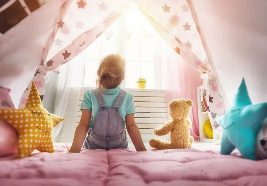 kinderzimmer-kinder-familie-zimmer-spielen-03 Kind mit Teddybär auf einem Bett